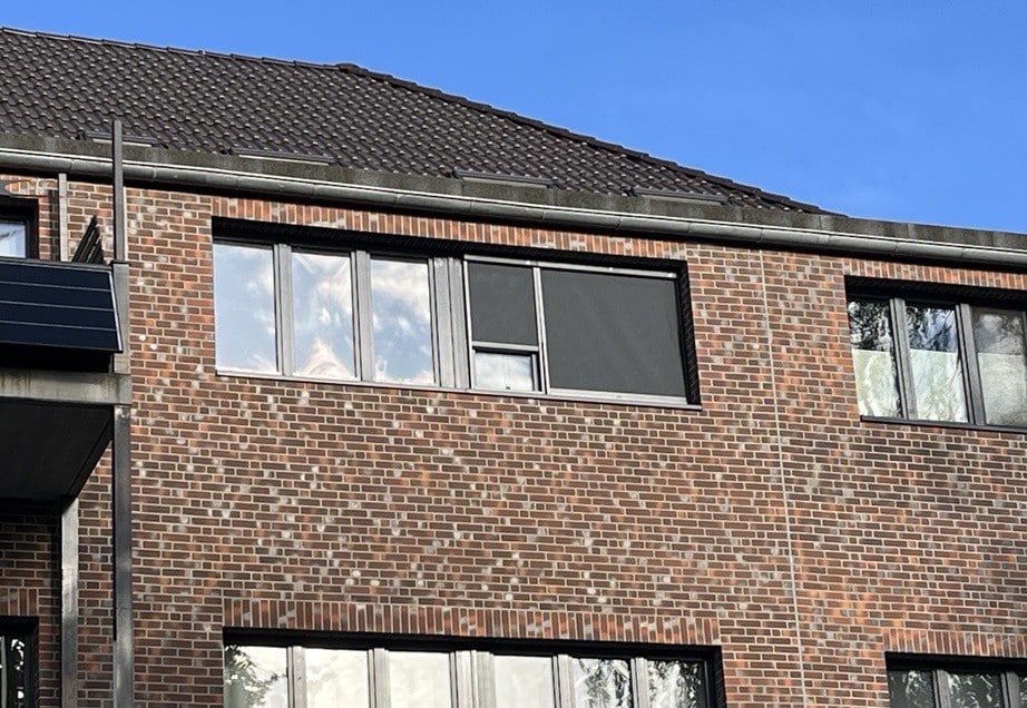 Fachada de ladrillo con persianas CLIP'N'SHADE en dos ventanas del exterior.
